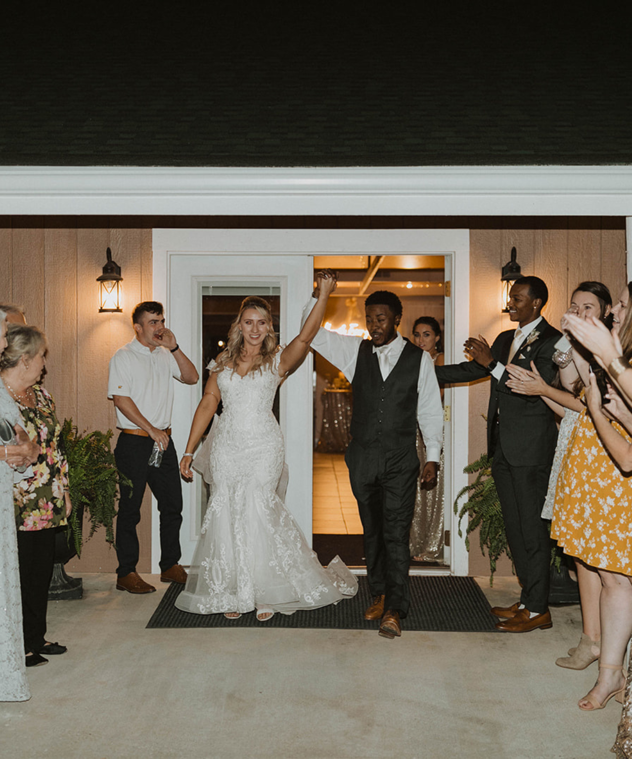 Bride wearing white dress and groom wearing white and black formal wear leaving their reception at white pine lodge to thunderous applause and joy. Its an elegant and luxurious send off for a wedding reception for all time. At white pine lodge of Fort Osage Christmas Tree farm and wedding venue in Kansas City