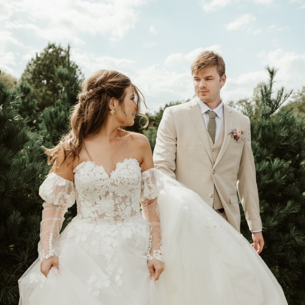 Woman wearing floral lace white wedding gown walks through Christmas 